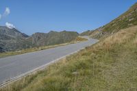 a motorcycle parked on a small mountain side road near mountains with no cars driving on it