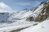 a man riding skis down a snow covered slope next to mountains near water and snow