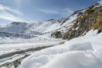 a man riding skis down a snow covered slope next to mountains near water and snow