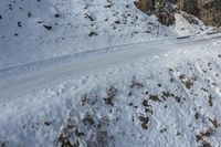 skiers make their way down a snowy mountain road under the sky overhead view of a trail