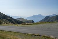 a motorcycle parked on a small mountain side road near mountains with no cars driving on it