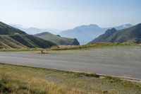 a motorcycle parked on a small mountain side road near mountains with no cars driving on it