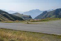 a motorcycle parked on a small mountain side road near mountains with no cars driving on it