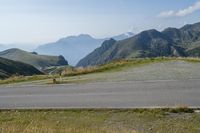 a motorcycle parked on a small mountain side road near mountains with no cars driving on it