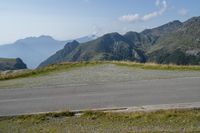 a motorcycle parked on a small mountain side road near mountains with no cars driving on it