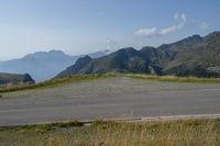 a motorcycle parked on a small mountain side road near mountains with no cars driving on it