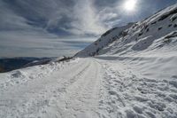 a long trail down a snowy mountain covered in snow at the bottom of a slope