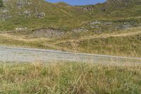 a motorcycle parked on a small mountain side road near mountains with no cars driving on it