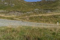 a motorcycle parked on a small mountain side road near mountains with no cars driving on it