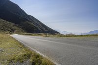 a motorcycle parked on a small mountain side road near mountains with no cars driving on it