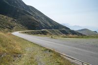 a motorcycle parked on a small mountain side road near mountains with no cars driving on it