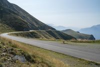 a motorcycle parked on a small mountain side road near mountains with no cars driving on it