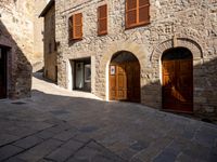 an image of a street in an old town in italy with wood doors and brown shutters