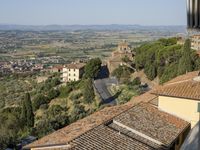 buildings in an italian village overlooks the valley and town below the roofline and hills