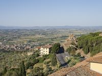 buildings in an italian village overlooks the valley and town below the roofline and hills