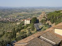 buildings in an italian village overlooks the valley and town below the roofline and hills