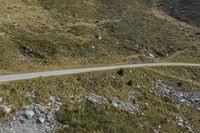 a motorcycle parked on a small mountain side road near mountains with no cars driving on it