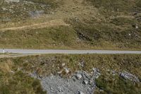 a motorcycle parked on a small mountain side road near mountains with no cars driving on it