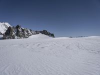 a large expanse of white snow on the top of a mountain with some rock formations