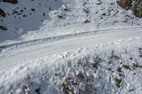 skier riding down the side of a snow covered slope on his skis and ski poles