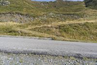 a motorcycle parked on a small mountain side road near mountains with no cars driving on it