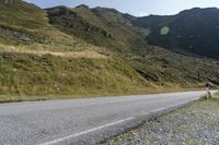 a motorcycle parked on a small mountain side road near mountains with no cars driving on it