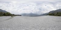 a view of a mountain and a beach and mountains through a glass looking panorama lens