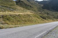 a motorcycle parked on a small mountain side road near mountains with no cars driving on it