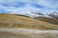 a large cow is grazing on a mountain with snow - covered mountains in the distance