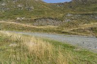 a motorcycle parked on a small mountain side road near mountains with no cars driving on it