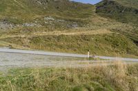 a motorcycle parked on a small mountain side road near mountains with no cars driving on it