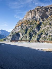 this is a mountain range with steep hills and mountains in the background, but also a paved roadway, the paved road goes downhill