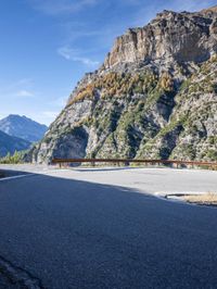 this is a mountain range with steep hills and mountains in the background, but also a paved roadway, the paved road goes downhill