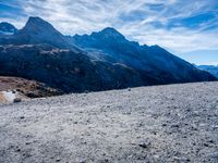 a large field with mountains in the background and some rocks and rocks on the ground