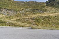 a motorcycle parked on a small mountain side road near mountains with no cars driving on it