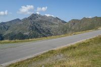 a motorcycle parked on a small mountain side road near mountains with no cars driving on it