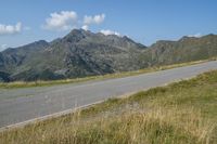 a motorcycle parked on a small mountain side road near mountains with no cars driving on it