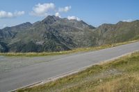 a motorcycle parked on a small mountain side road near mountains with no cars driving on it