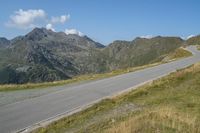 a motorcycle parked on a small mountain side road near mountains with no cars driving on it