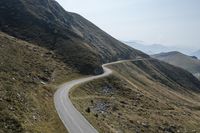 a motorcycle parked on a small mountain side road near mountains with no cars driving on it