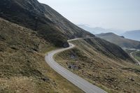 a motorcycle parked on a small mountain side road near mountains with no cars driving on it