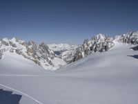 a person skiing on a snowy slope in a blue sky and mountain range behind them