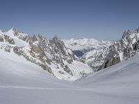 a person skiing on a snowy slope in a blue sky and mountain range behind them