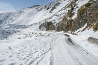 a mountain with tracks of snow on it's side and a road that is covered with snow