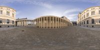 a panoramic view shows the circular exterior on the building and in the foreground is an oval structure with pillars