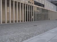 a man is holding an umbrella walking down the sidewalk from an office building on a sunny day