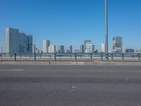 the highway and bridge leading to a city in japan and has tall buildings and blue skies