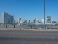 the highway and bridge leading to a city in japan and has tall buildings and blue skies