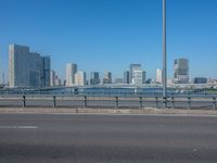 the highway and bridge leading to a city in japan and has tall buildings and blue skies