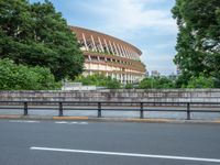 a view of a stadium from the street, showing many trees and bushes in the distance